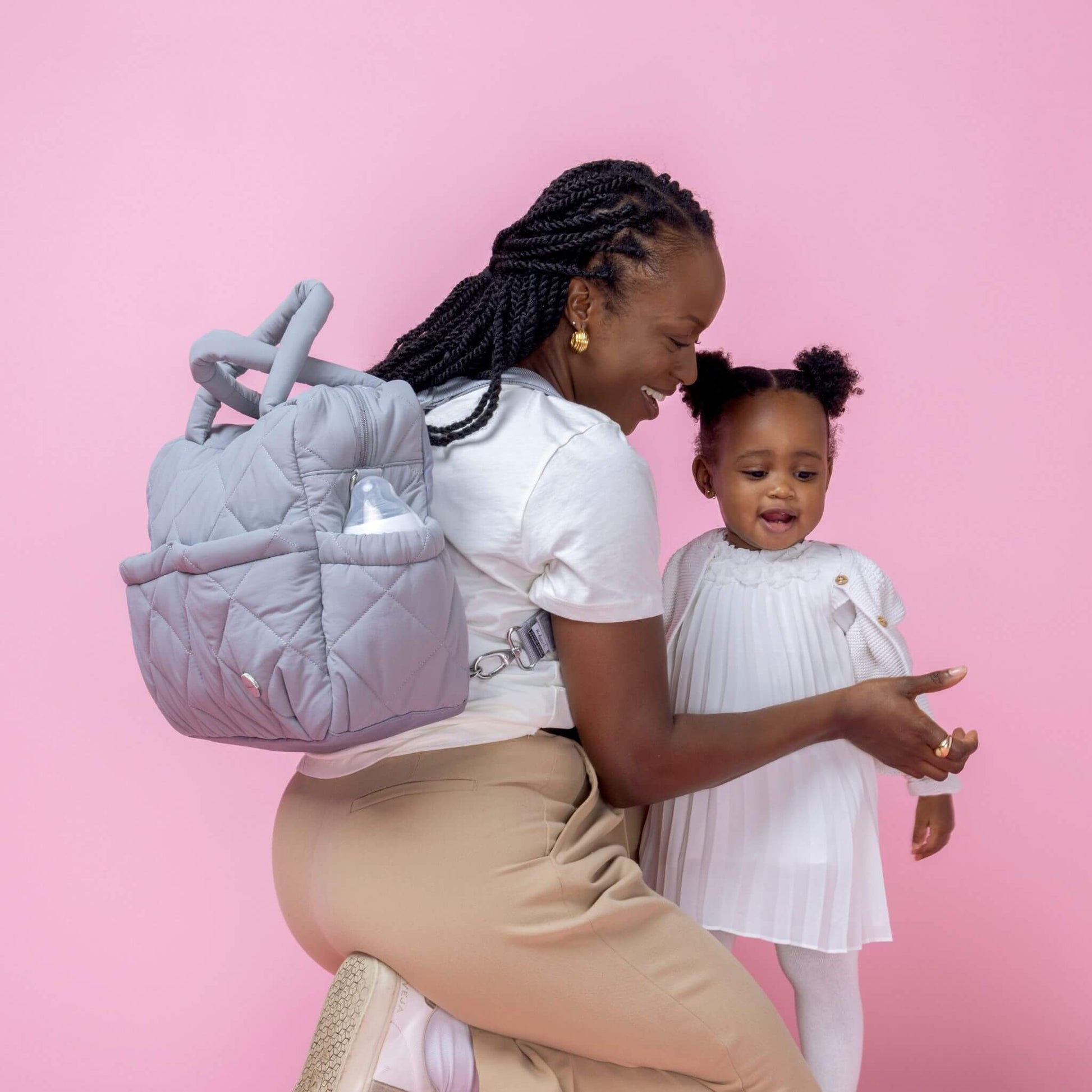 Babymel Willow Convertible Changing Bag in duck egg grey, worn as a backpack by a mother interacting with her toddler, highlighting its hands-free design.