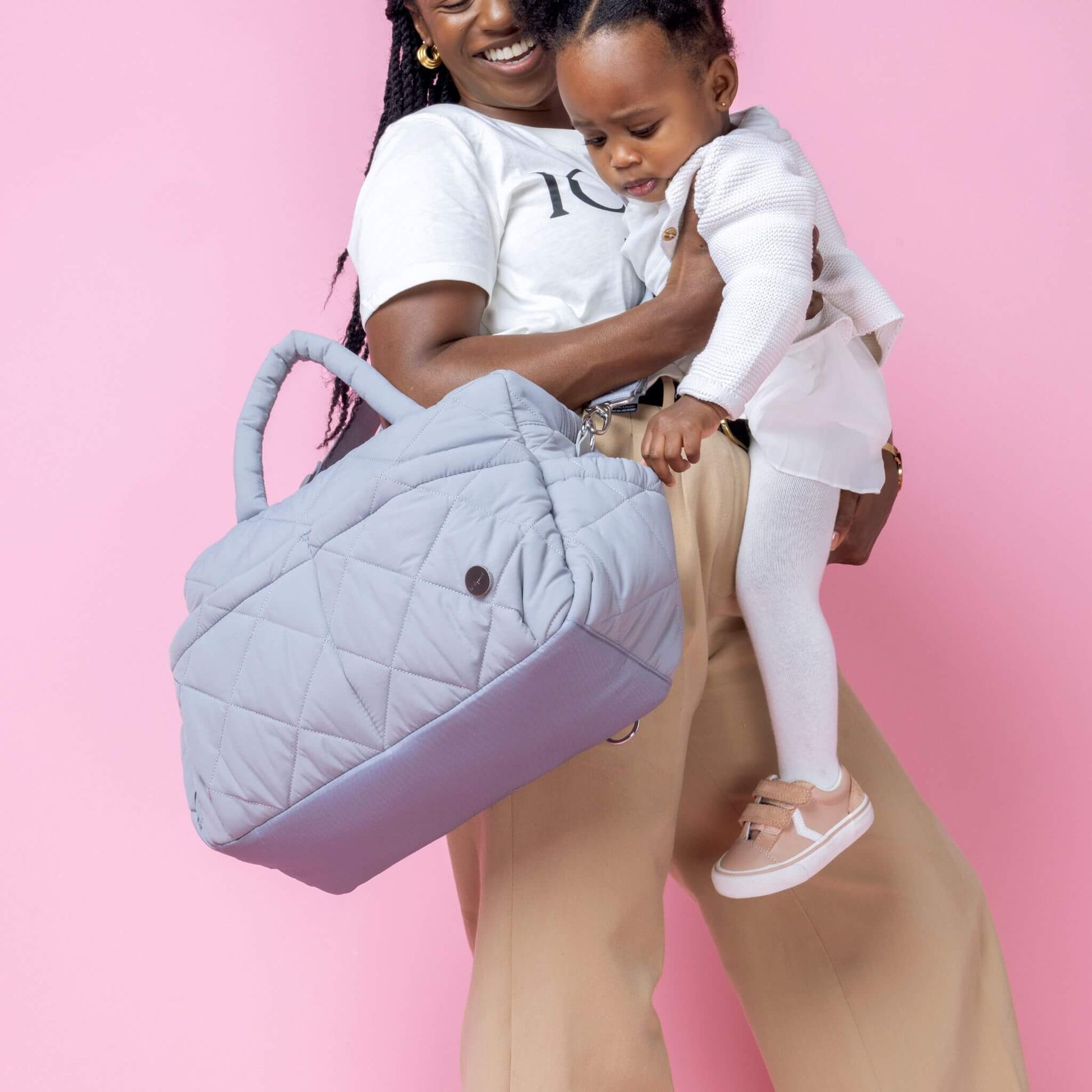 Babymel Willow Convertible Changing Bag in duck egg grey, carried crossbody by a smiling mother holding her toddler, highlighting its spacious design.