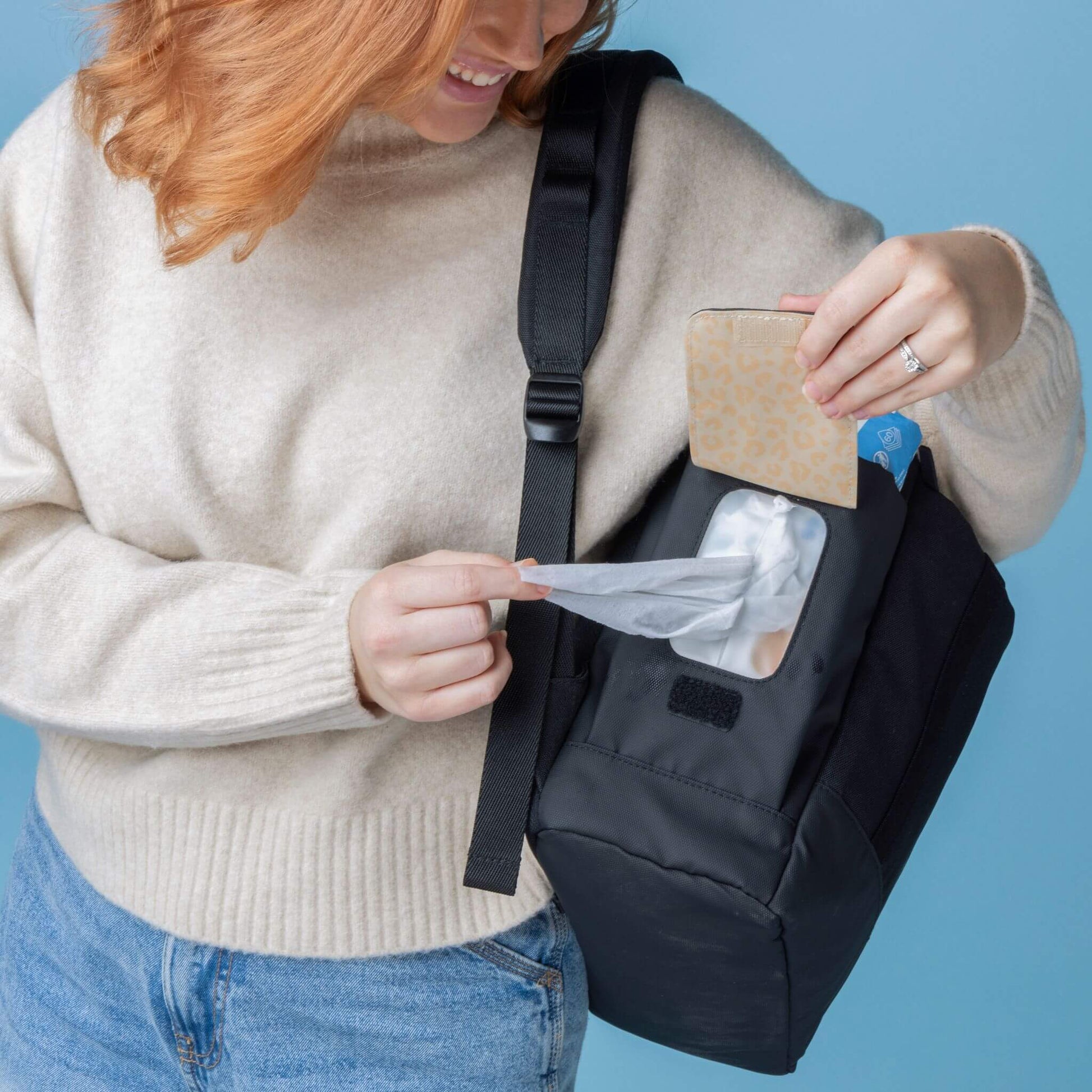 Parent accessing the easy-wipes side pocket of the Babymel Finn Changing Backpack in Black, demonstrating its convenient and practical design for quick clean-ups on the go