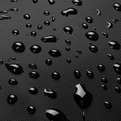 Close-up of the waterproof fabric on the Babymel Finn Changing Backpack in Black, with water droplets beading on the durable, textured material.