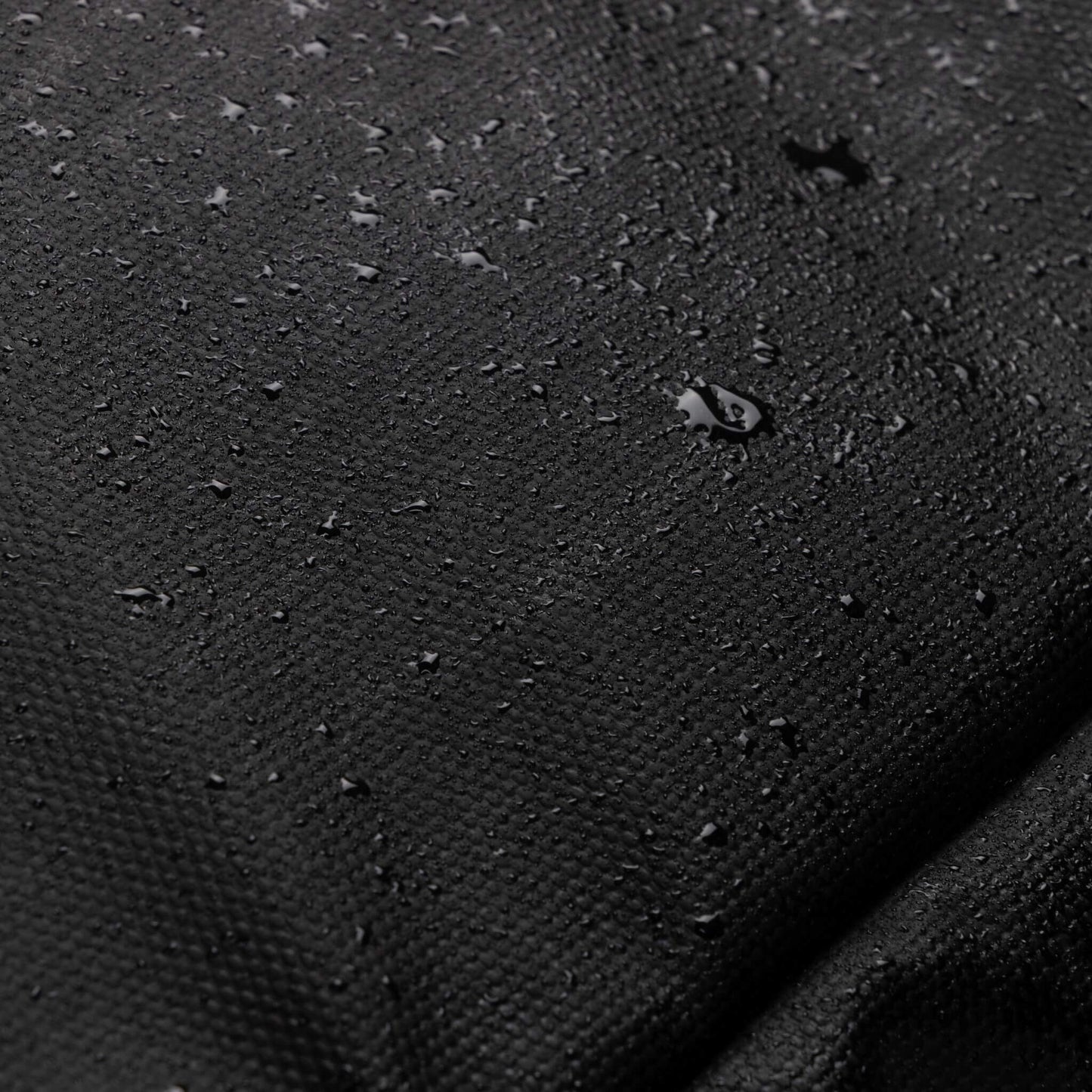 Detailed view of the water-resistant fabric on the Babymel Finn Changing Backpack in Black, demonstrating its durability and ability to repel water effectively.