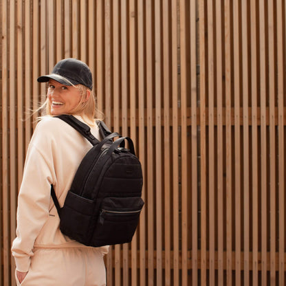 Smiling person wearing the Babymel Lola Eco Backpack in Black, showcasing its sleek, comfortable, and stylish design for everyday use.