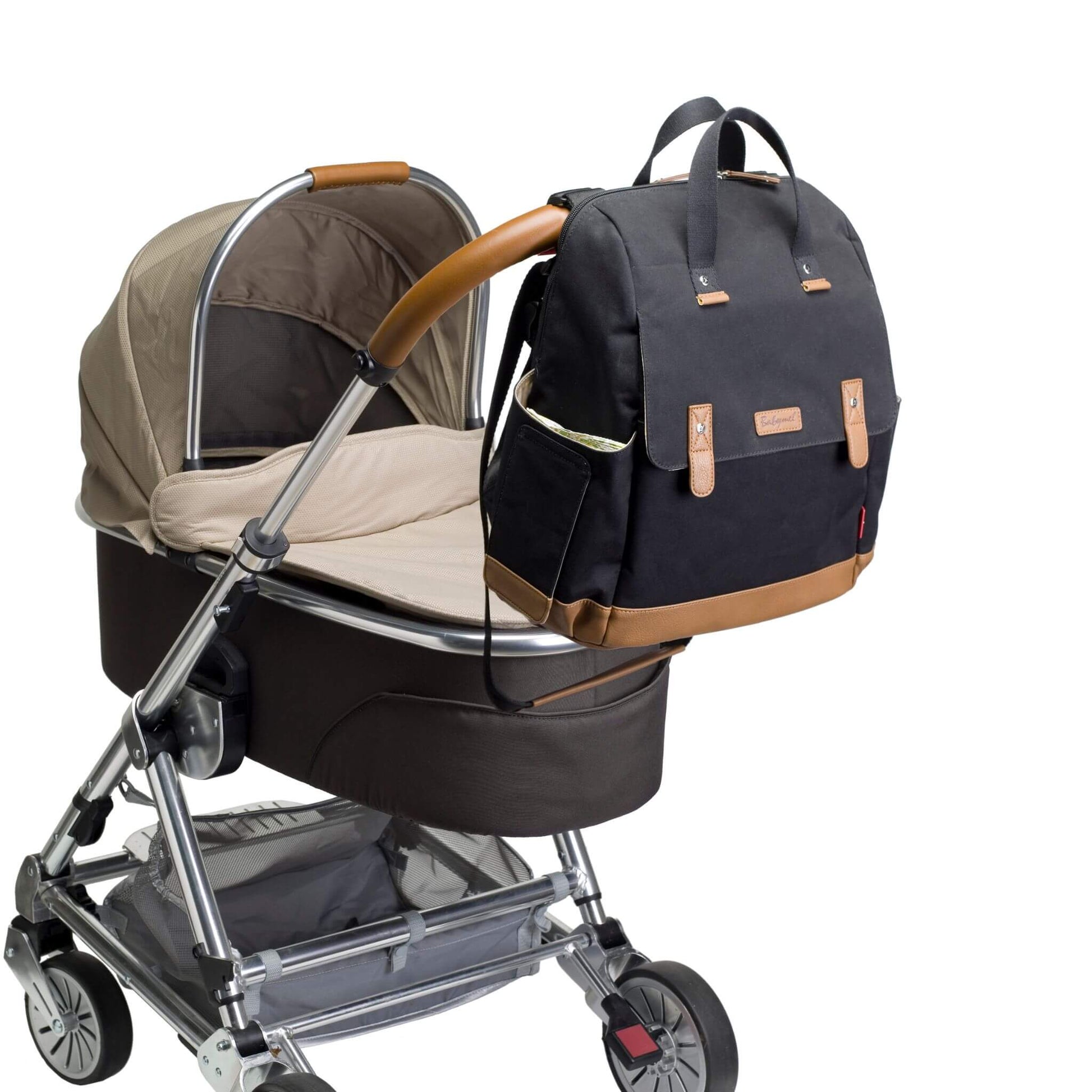 Black Babymel Robyn Eco Convertible Backpack with tan details, securely attached to a pram using built-in stroller straps for hands-free convenience.