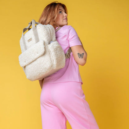 Woman wearing the cream Babymel Teddy Convertible Backpack with soft borg fleece, styled as a backpack, highlighting its cosy and functional design.