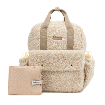 Cream Babymel Teddy Convertible Backpack made from soft borg fleece, shown with included padded changing mat and side pockets holding baby bottles.