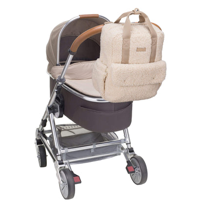 Cream Babymel Teddy Convertible Backpack with soft borg fleece, securely attached to a pram using built-in stroller clips for hands-free convenience.