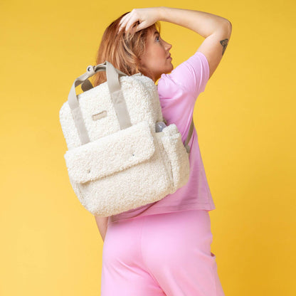 Woman wearing the cream Babymel Teddy Convertible Backpack with soft borg fleece, styled as a backpack, highlighting its cosy and stylish design.