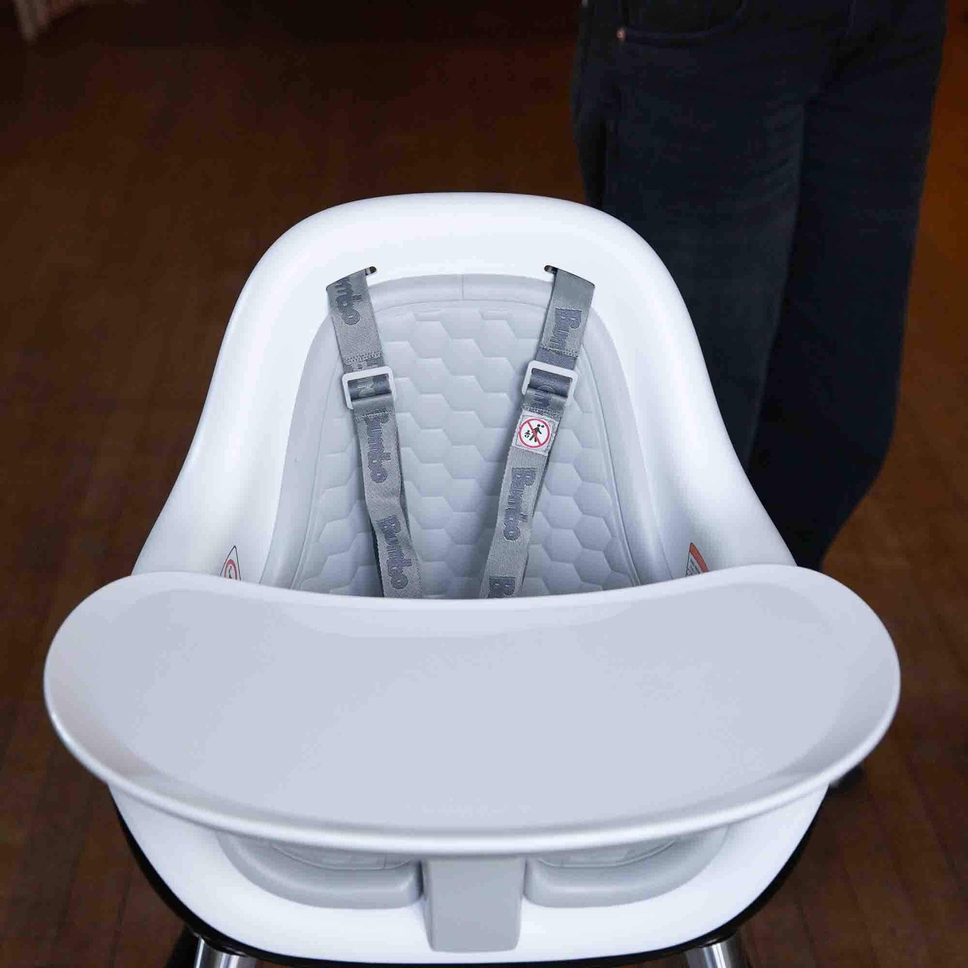 Close-up of Bumbo highchair in cool grey, featuring a secure harness, honeycomb-patterned seat padding, and a detachable tray.