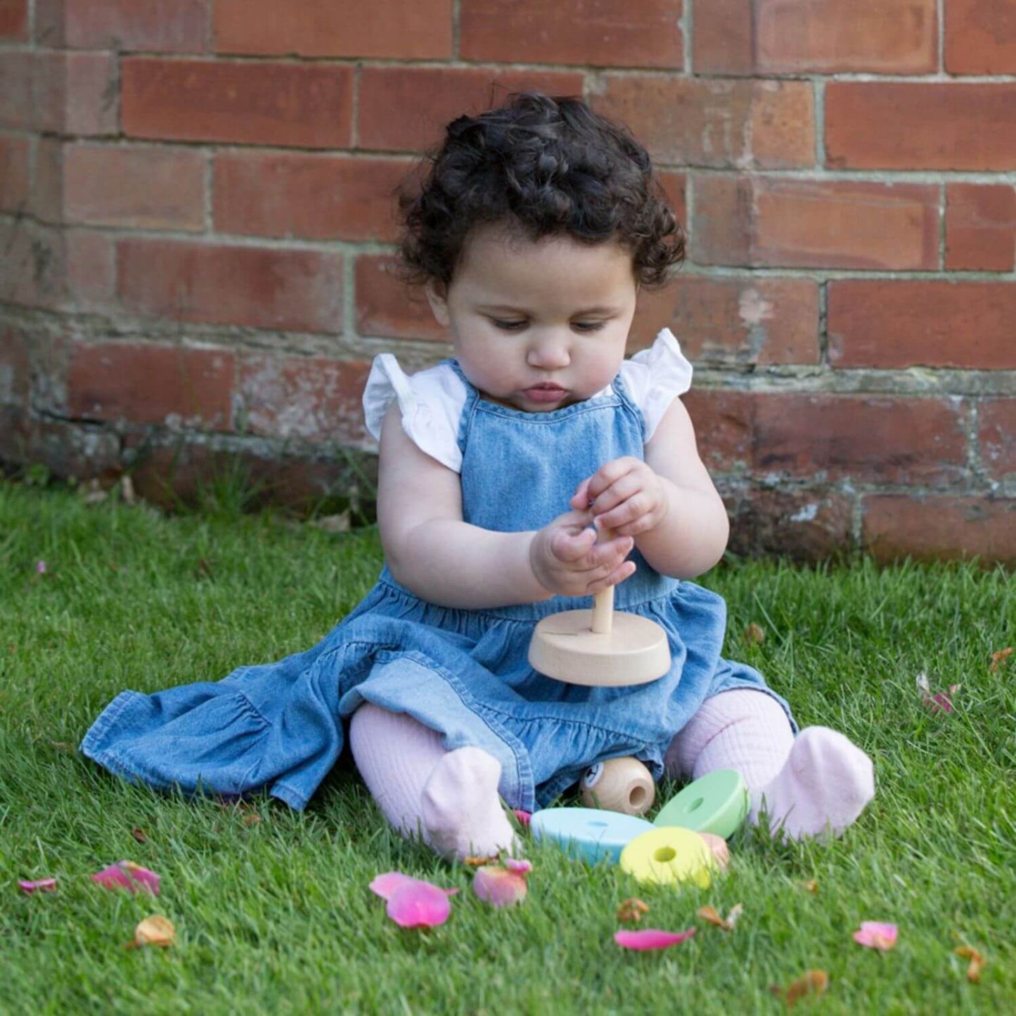 Child playing outdoors with the Classic World Bear Tower, stacking colourful wooden rings to develop coordination and fine motor skills.