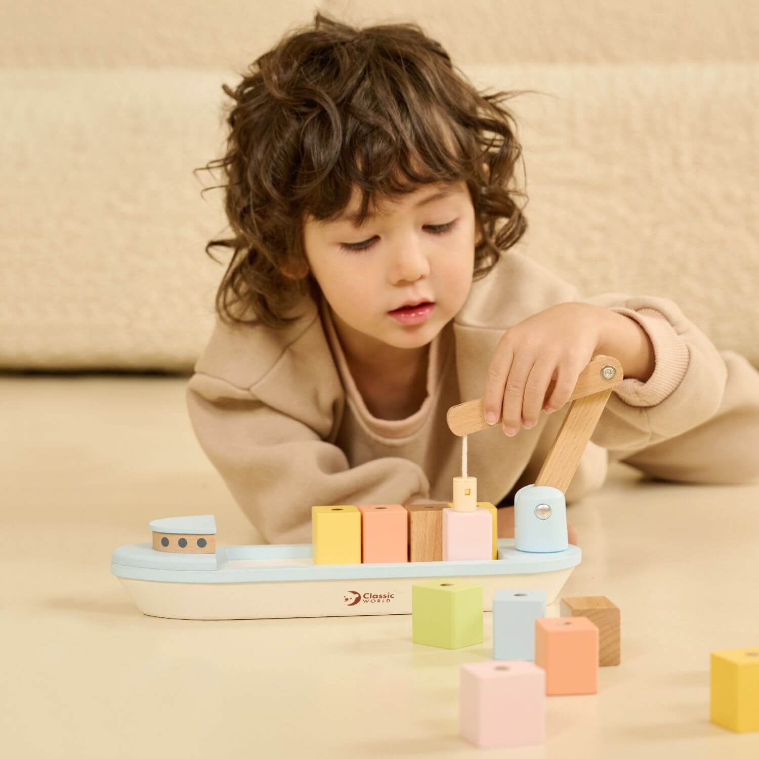 Child engaging with the Classic World Block Boat, stacking colourful wooden blocks using the magnetic derrick for creative play.