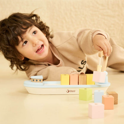 Child playing with the Classic World Block Boat, using the flexible magnetic derrick to load colourful wooden cargo blocks.