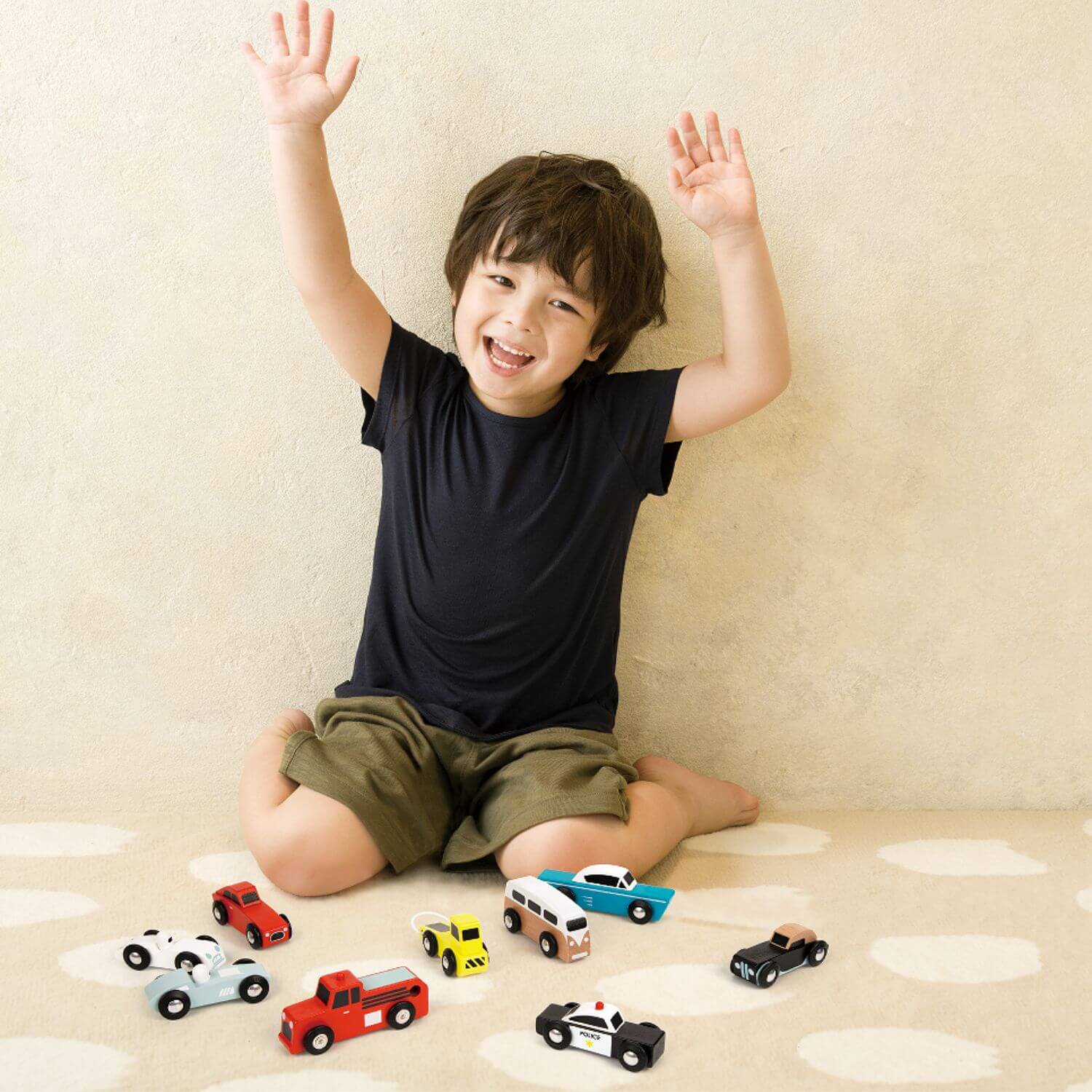 Child joyfully playing with a collection of Classic World wooden toy cars.