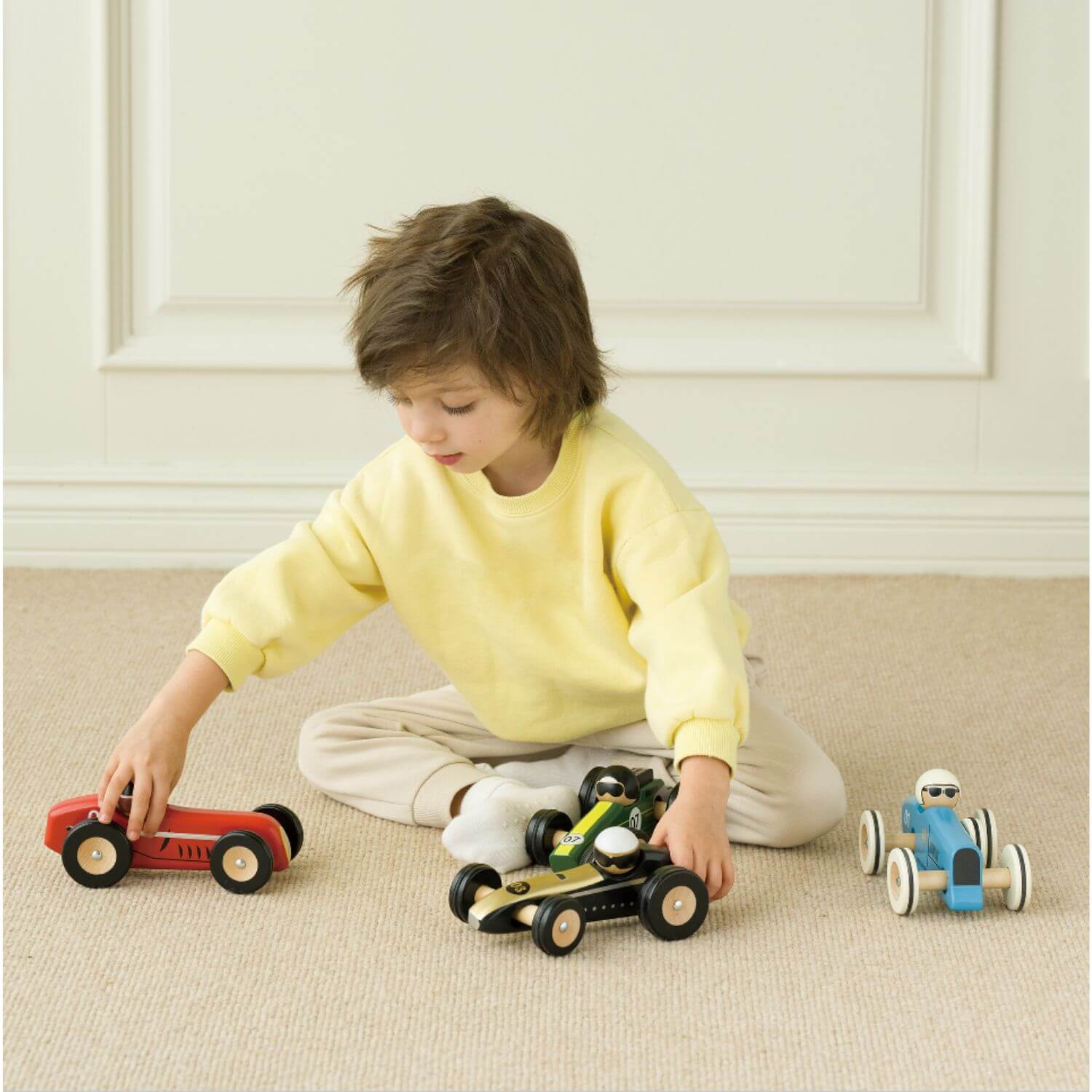 Child playing with Classic World wooden race cars, featuring sleek designs, perfect for imaginative play.