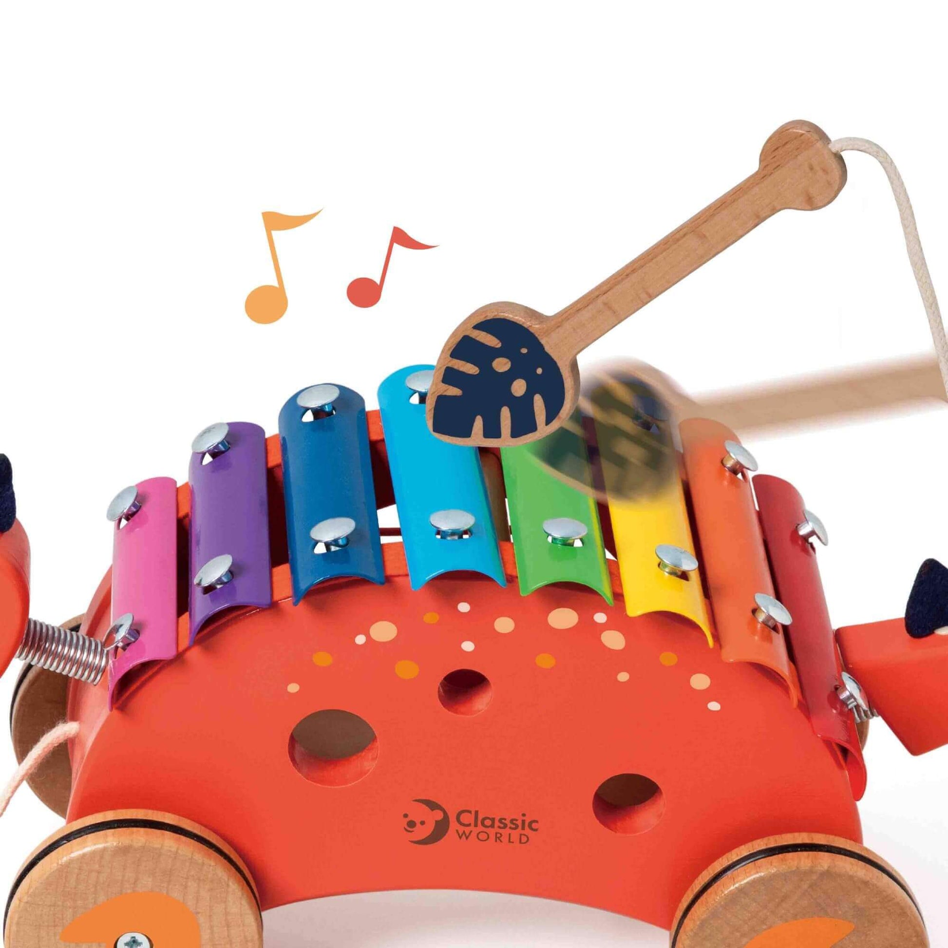 Close-up of the Classic World Dinosaur Xylophone being played with its wooden mallet, showcasing colourful keys and musical notes.