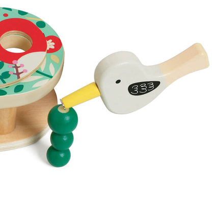 A close-up of the Classic World Doctor Woodpecker toy, showing the magnetic bird tool picking up a green worm with its yellow beak.