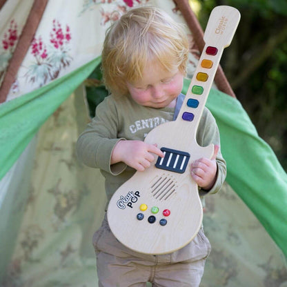 Child joyfully playing the Classic World Electric Glowing Wooden Guitar, featuring colourful keys and interactive sound effects outdoors.