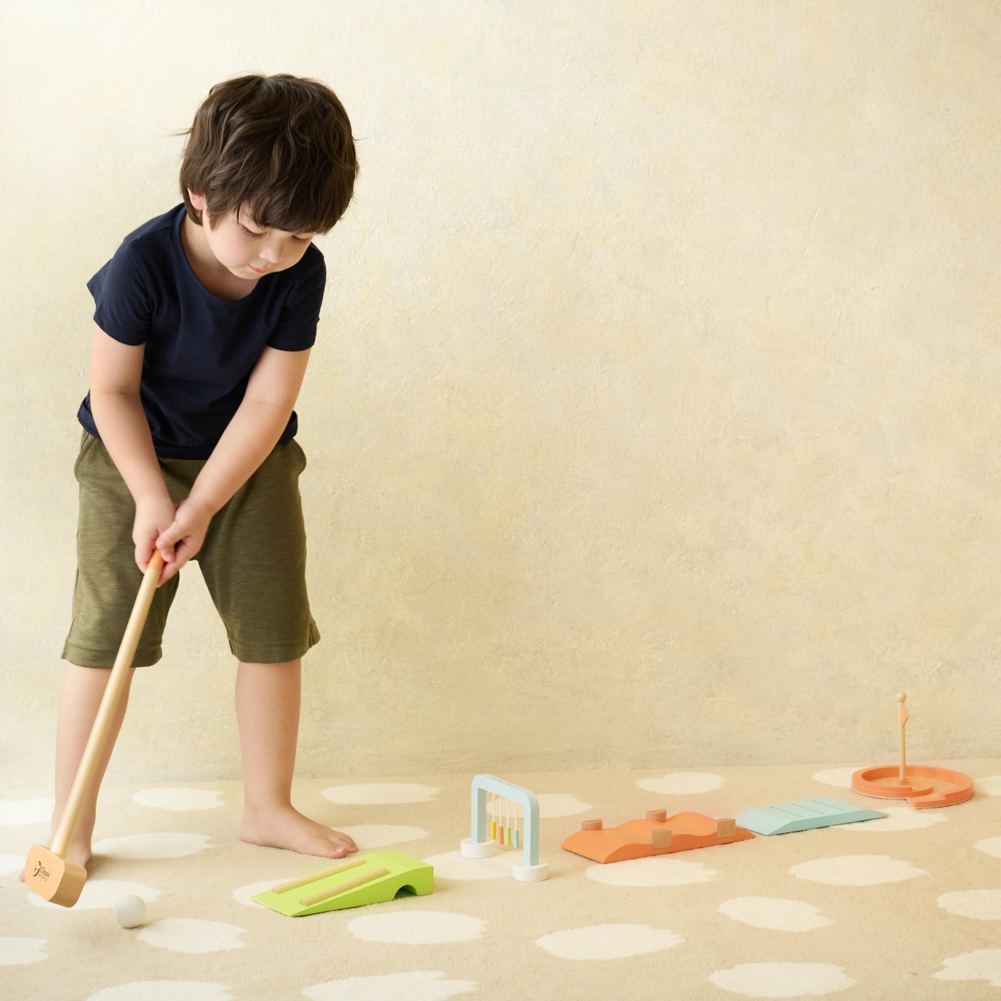 Child playing with the Classic World wooden golf set, focusing on colourful obstacles, a wooden mallet, and ball for imaginative play.