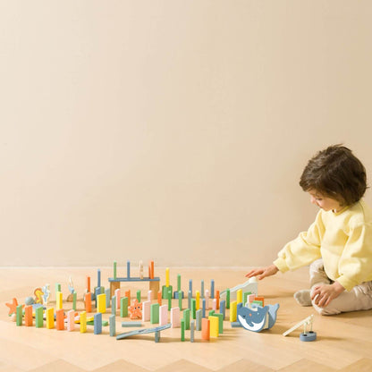 A child playing with the Classic World Ocean Dominoes, arranging colourful sea-themed pieces to create a fun and interactive domino chain.