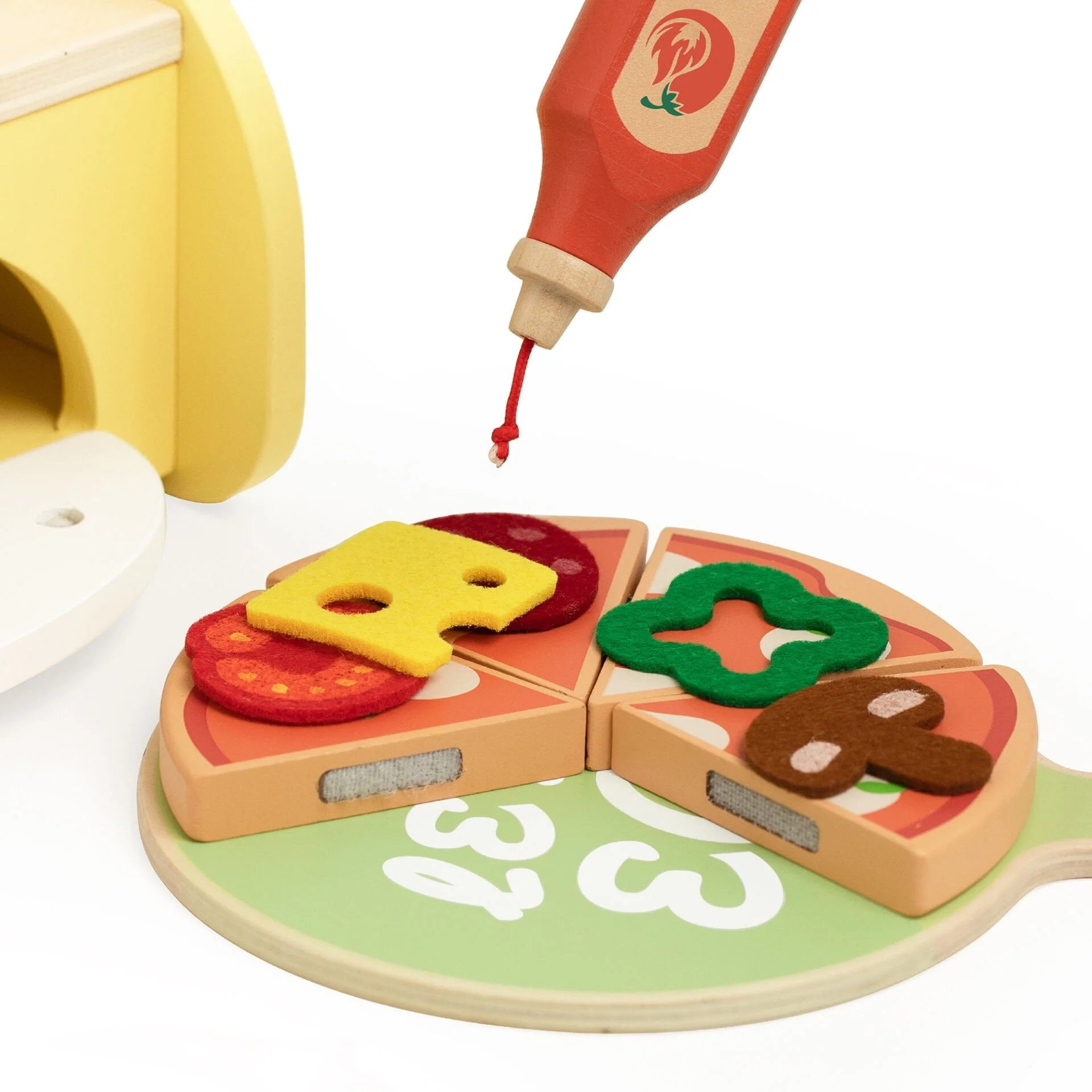 Close-up of the Classic World Pizza Oven set showing wooden pizza slices with colourful felt toppings and a bottle of pretend sauce for imaginative play.