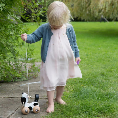 Child pulling the Classic World Pull Dog outdoors, enjoying an engaging and interactive walking experience with this charming wooden toy.