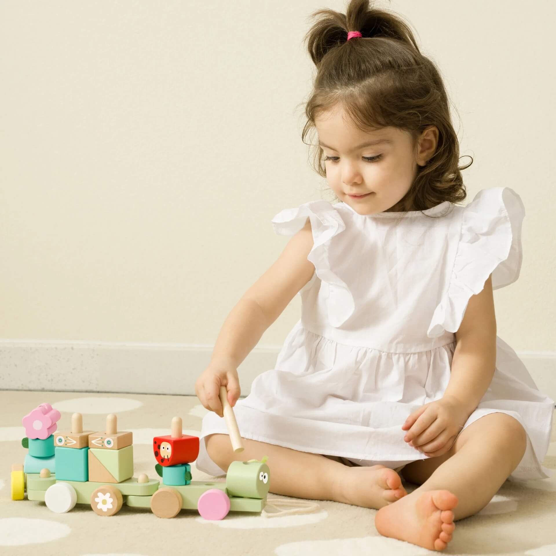 Child playing with the Classic World Pull Jungle toy, arranging colourful wooden blocks on the caterpillar train for imaginative and creative fun.