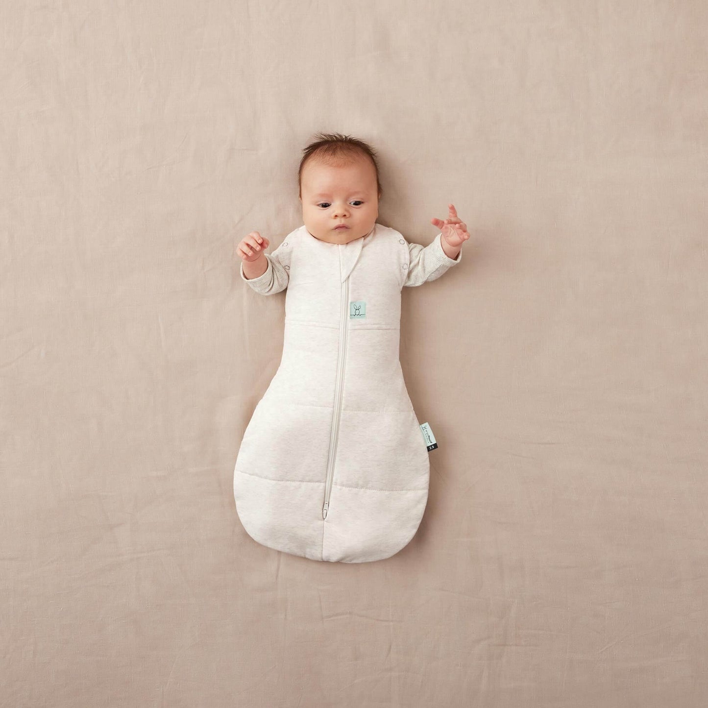 Baby in ErgoPouch Winter 2.5 tog cocoon swaddle bag, oatmeal colour, arms fully unswaddled.