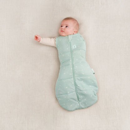 Baby in ErgoPouch Winter 2.5 tog cocoon swaddle bag, sage colour, arm partially unswaddled.