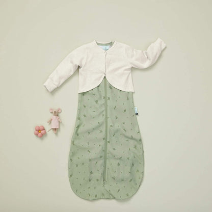 ErgoPouch Long Sleeved Arm Warmer in oatmeal paired with a green sleeping bag, laid flat with a toy mouse and flower. A soft, breathable sleep layer.