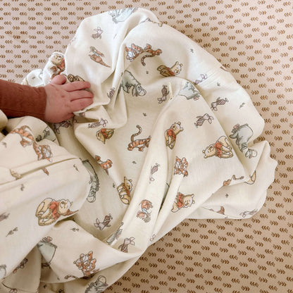 Baby's hand resting on the HALO® SleepSack® showing the soft 0.5 Tog fabric with Winnie the Pooh characters, perfect for warmer room temperatures.