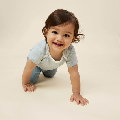 Smiling baby wearing a MORI blue stripe short sleeve bodysuit, crawling on the floor with hands extended.