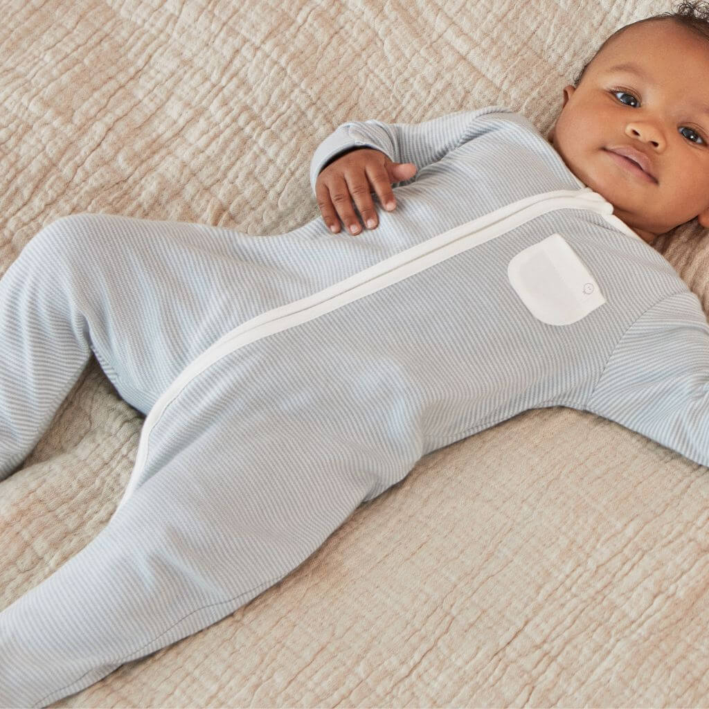 Baby wearing the MORI Clever Zip Sleepsuit in blue stripe, featuring a front zip closure and a small white pocket, designed for comfort and easy changing.