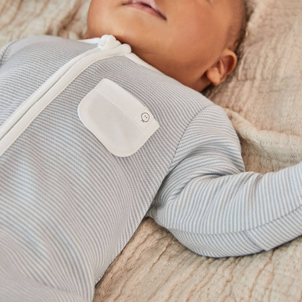 Close-up of a baby wearing the MORI Clever Zip Sleepsuit in blue stripe, featuring a front zip and a small white pocket, designed for comfort and convenience.