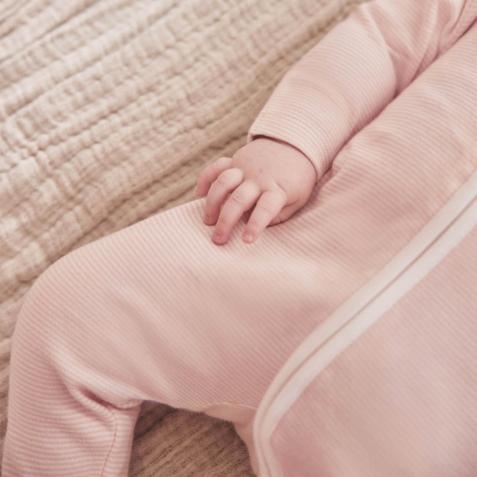 Close-up of a baby wearing the MORI Clever Zip Sleepsuit in blush stripe, showing the soft fabric and two-way front zip for easy changes and comfort.