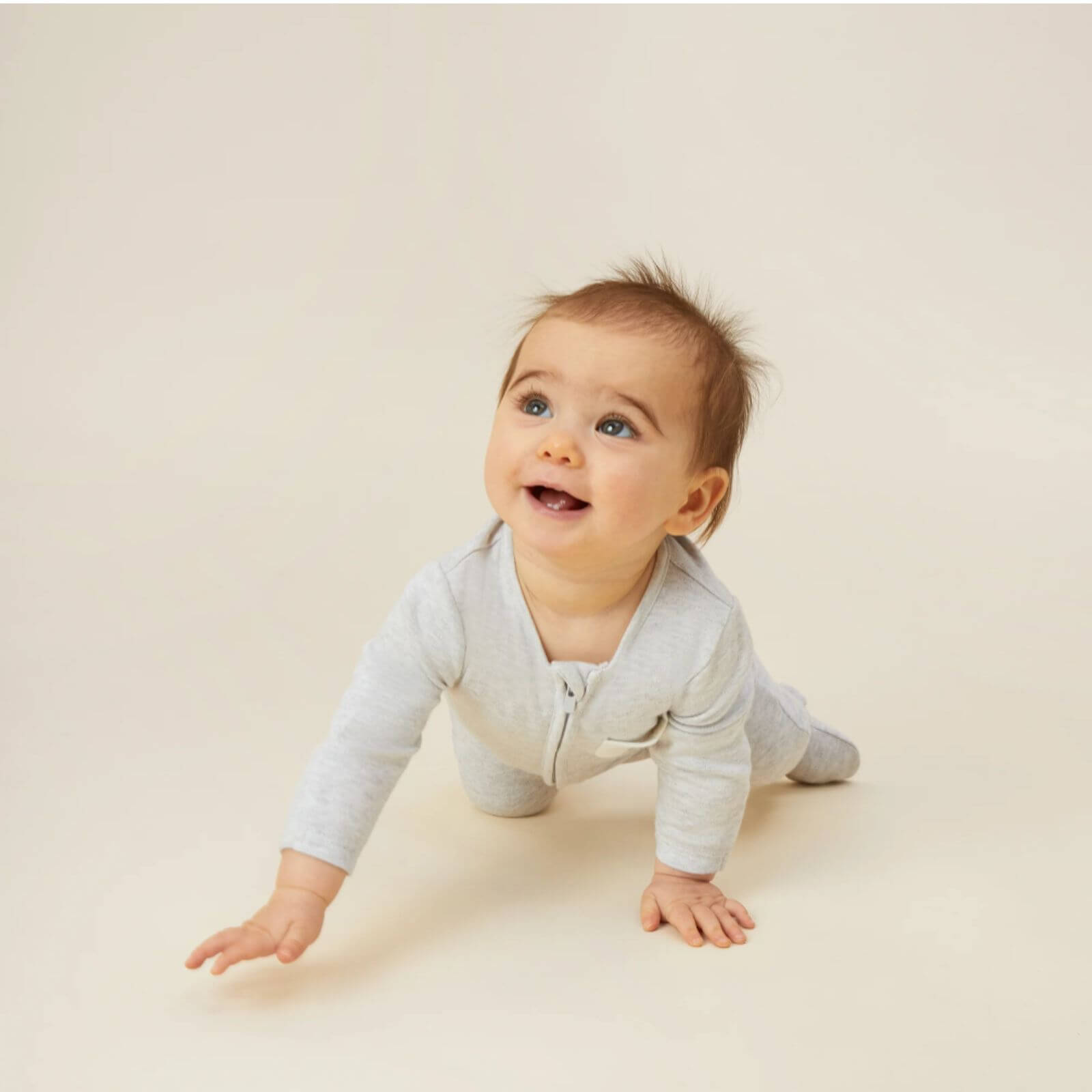 Baby crawling while wearing the MORI Clever Zip Sleepsuit in grey, featuring a two-way front zip and a small chest pocket, designed for comfort and easy movement.