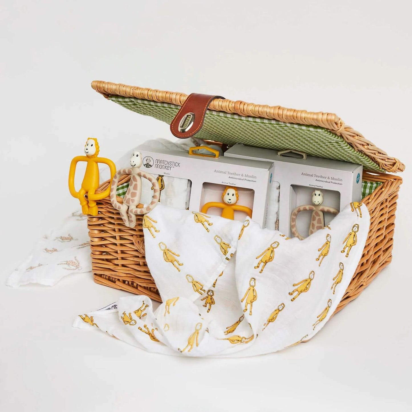 Matchstick Monkey animal teether and muslin gift set displayed in a wicker basket, featuring lion and giraffe teethers with matching muslin cloths.