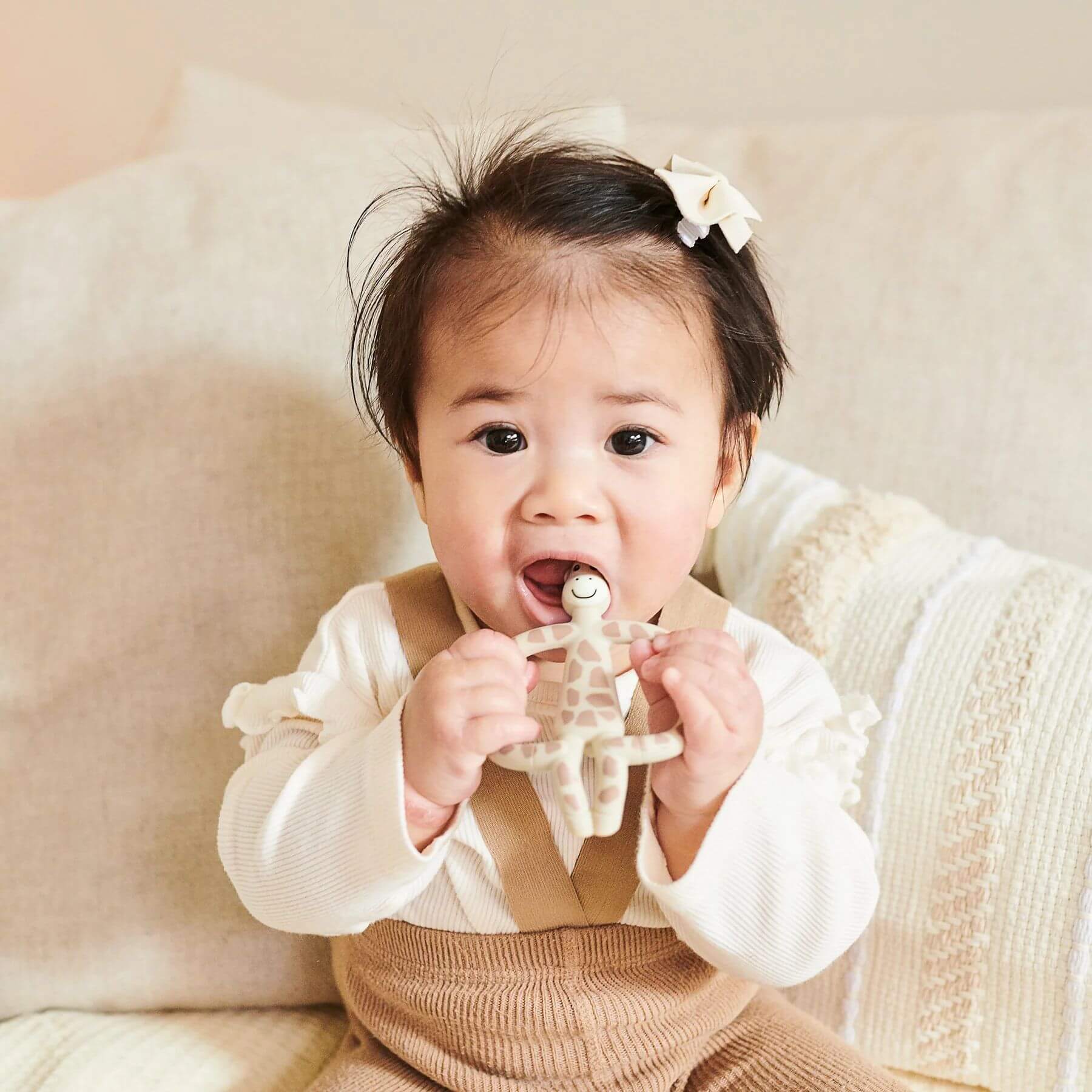 Baby holding and chewing on Matchstick Monkey giraffe teether, designed to soothe gums and provide teething relief.