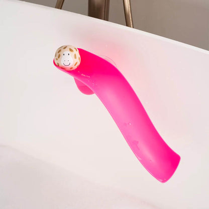 Pink Matchstick Monkey slide attached to the side of a bathtub with a beige giraffe animal rock at the top, designed for toddler bath time play.