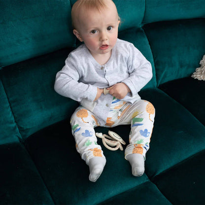 Baby sitting on a sofa with the Gigi Giraffe Matchstick Monkey teething starter set, featuring flat and animal teethers, ideal for soothing gums during teething.