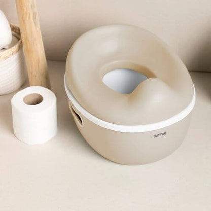 The Nattou potty placed in a bathroom setting next to a roll of toilet paper, blending seamlessly into the space.