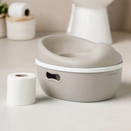 Image of the beige Nattou potty, showcasing its compact and stylish  look, with a bathroom in the background. 