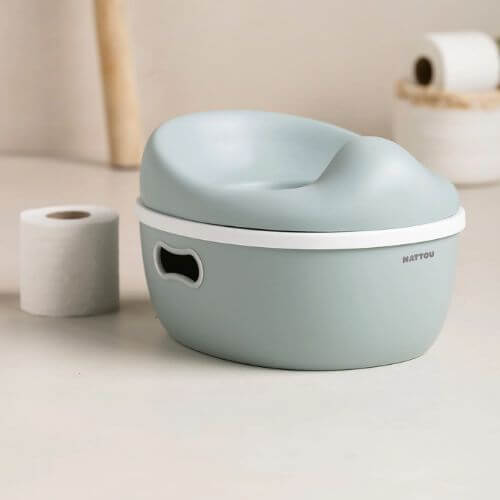  Nattou 3-in-1 potty placed in a bathroom setting next to a roll of toilet paper, blending seamlessly into the space.