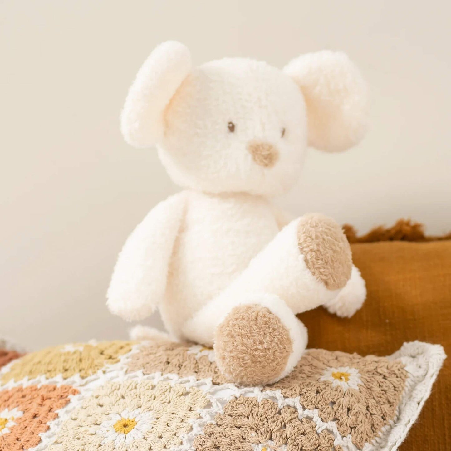 Nattou cream mouse plush toy sitting on textured boho cushion, showcasing soft plush texture and tan paw details.