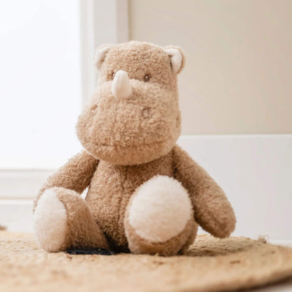 Nattou Teddy Cuddly rhino plush toy sitting on textured rug, featuring plush tan fur and white paw detail.