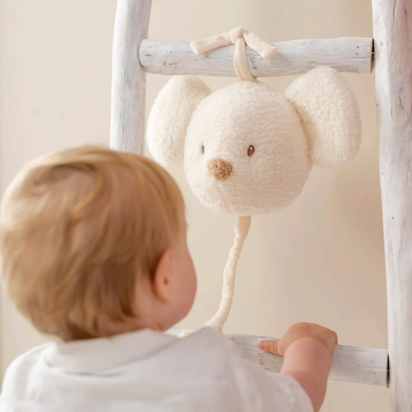 Baby reaching for the Nattou Teddy Musical Mouse, intrigued by its plush texture and gentle music.