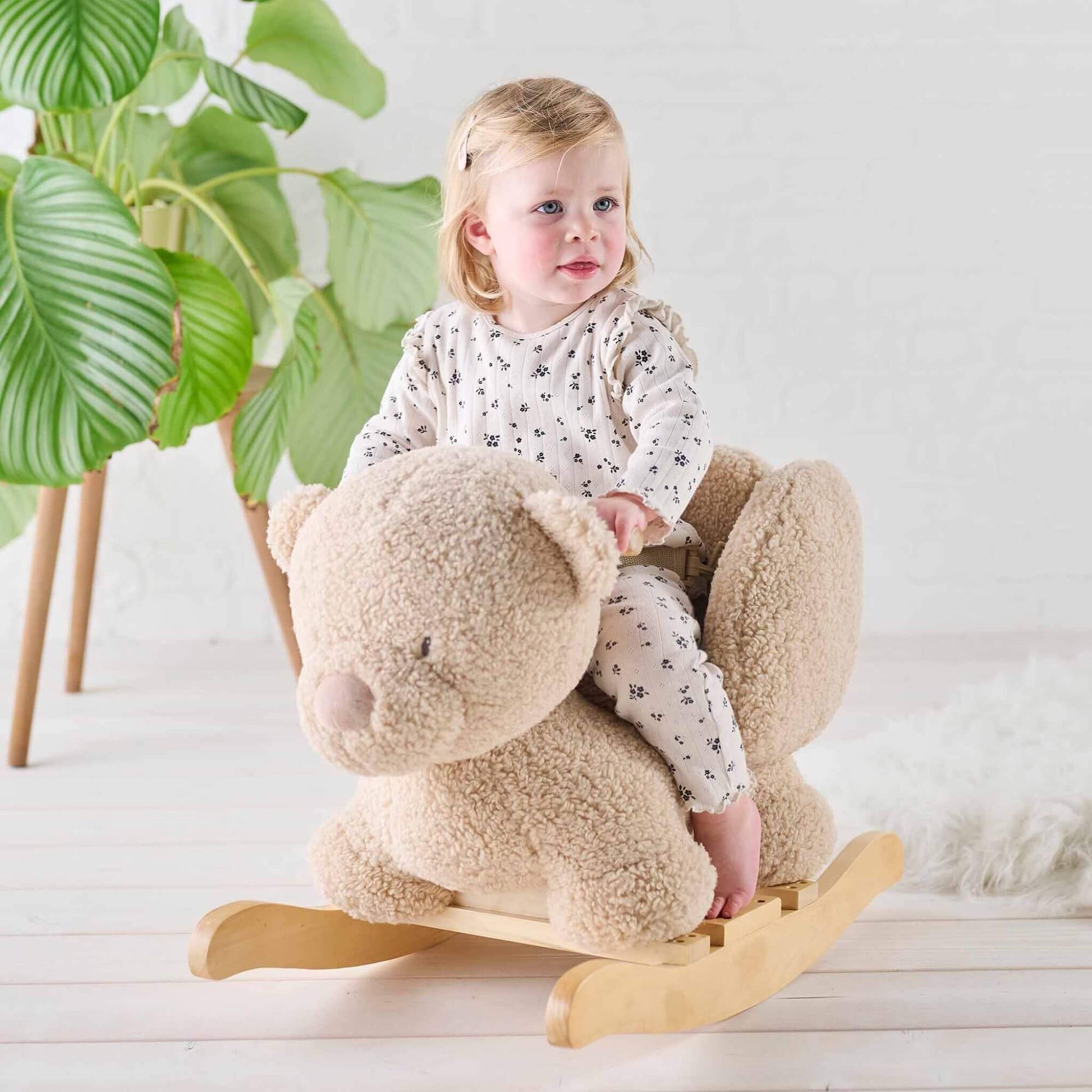 Smiling toddler riding the Nattou Teddy Bear Rocker in a cosy, light-filled room with soft textures and natural wooden accents.