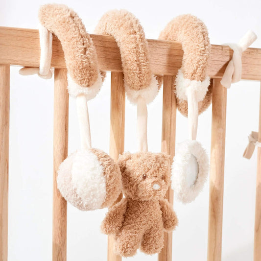 Nattou spiral crib toy featuring soft plush teddy bear and textured balls, mounted on wooden nursery furniture.