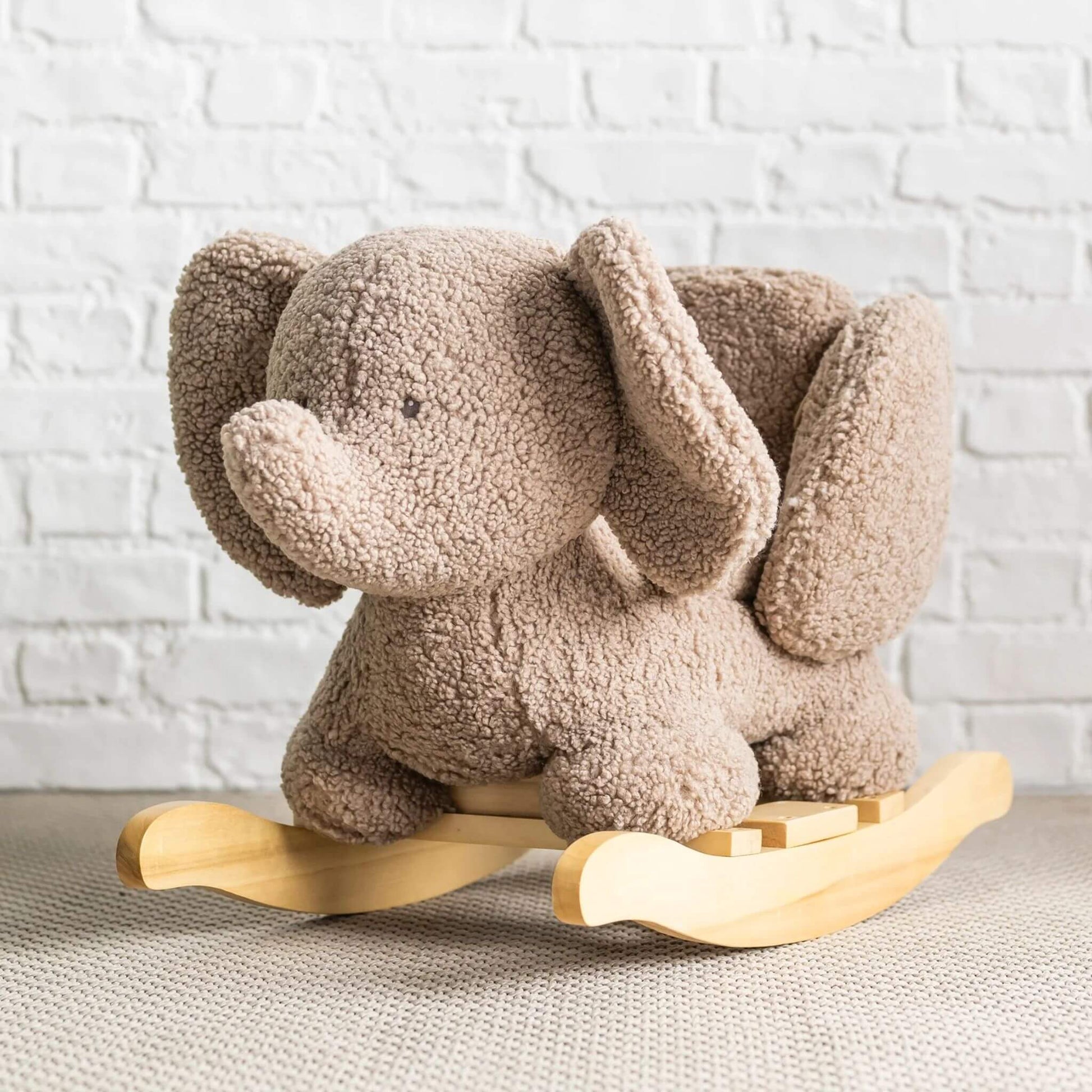 Nattou Teddy Elephant Rocker in taupe, set against a backdrop with a white brick wall and soft flooring.