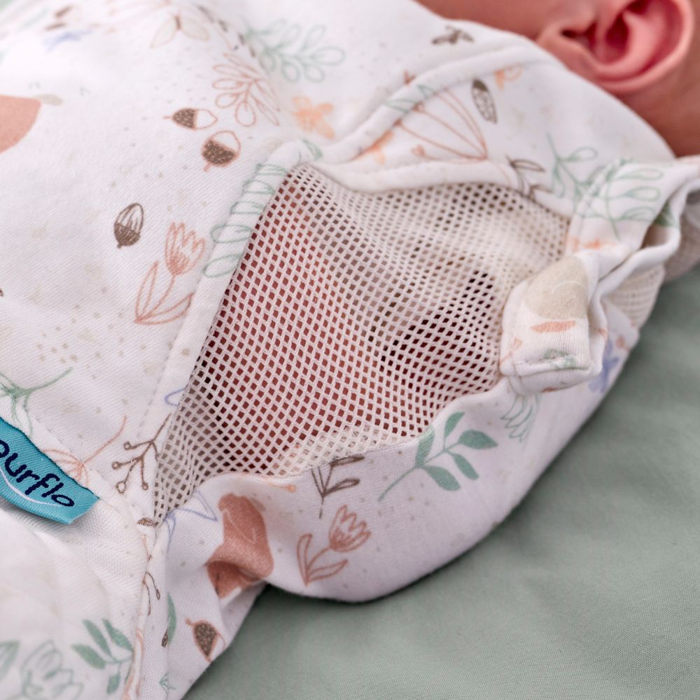 Close-up of the Purflo Swaddle to Sleep Bag 0.5 Tog in Storybook Nutmeg. Features breathable mesh panels and soft fabric with a woodland print.