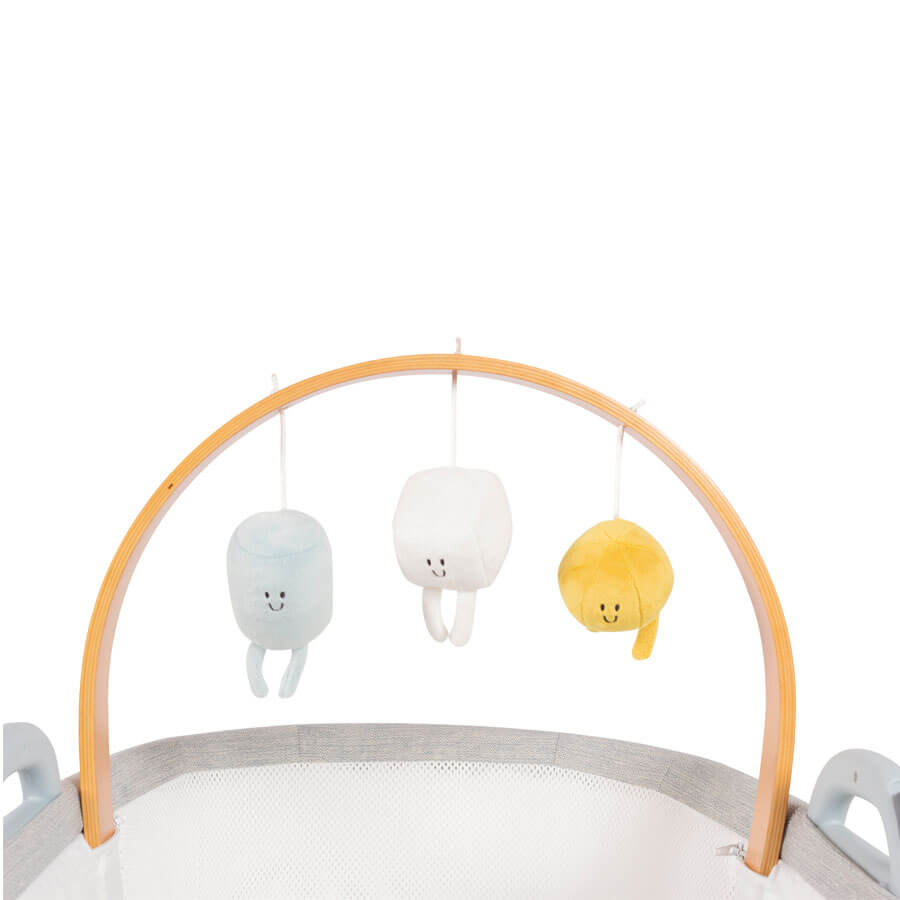 Close-up of Purflo breathable crib's wooden mobile arch, featuring three soft plush toys in pastel blue, white, and yellow with smiling faces.