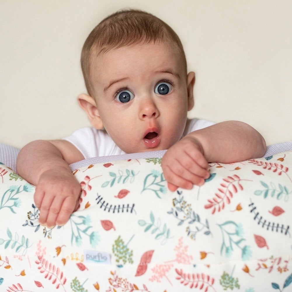 Baby peeking over the Purflo Breathe Pregnancy Pillow in Botanical print, showcasing the soft and colourful design with a nature-inspired pattern.